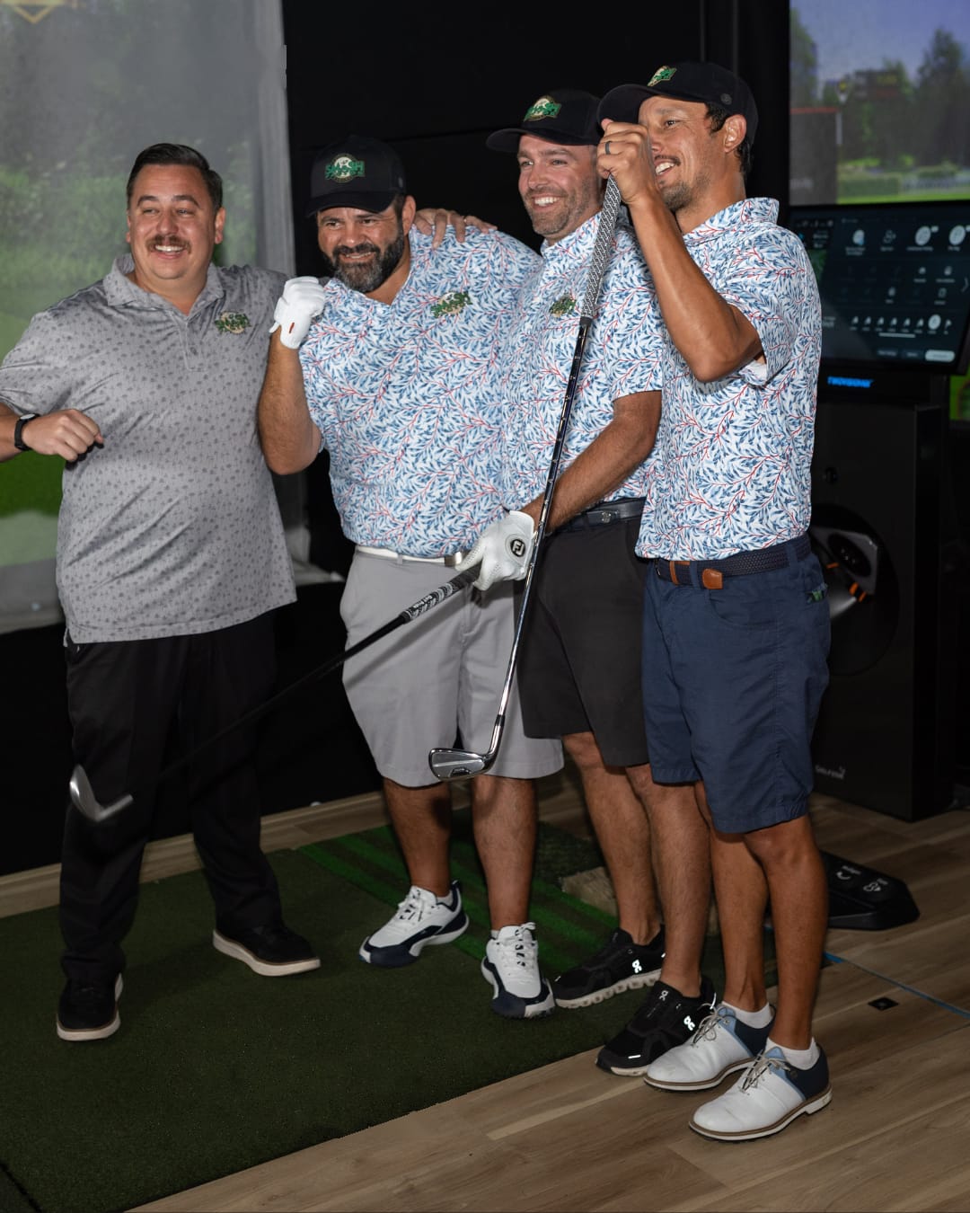 Four players in matching Smash Factor shirts and caps celebrating together in a bay.